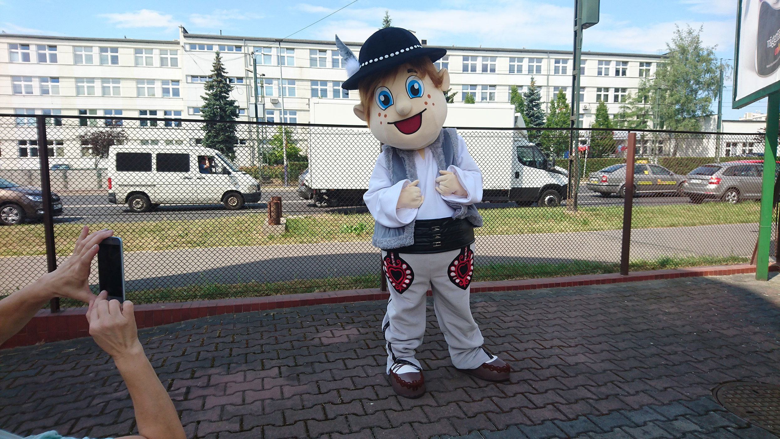 Na fotografii widnieje kostium reklamowy w postaci górala, pozujący do zdjęcia przed siedzibą firmy Elabika